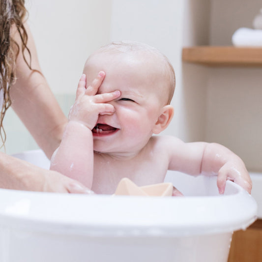 Un bébé rit dans sa baignoire pendant le bain