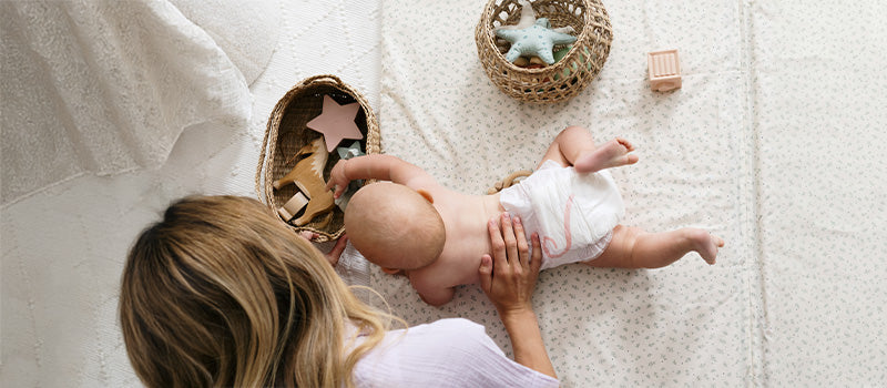 Un bébé sur le ventre joue avec sa maman.