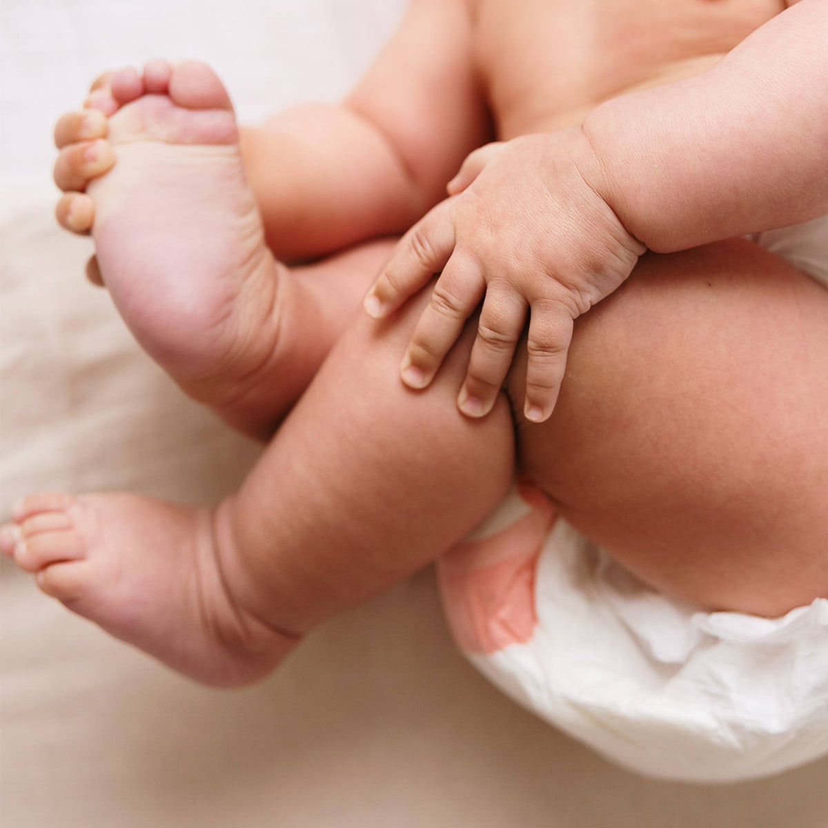 Gros plan sur les pieds et les mains d’un bébé portant une couche Biolane