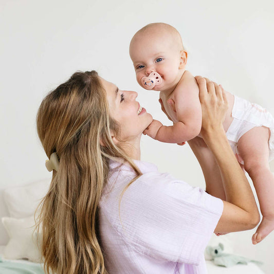 Une maman soulève son bébé en couche Biolane