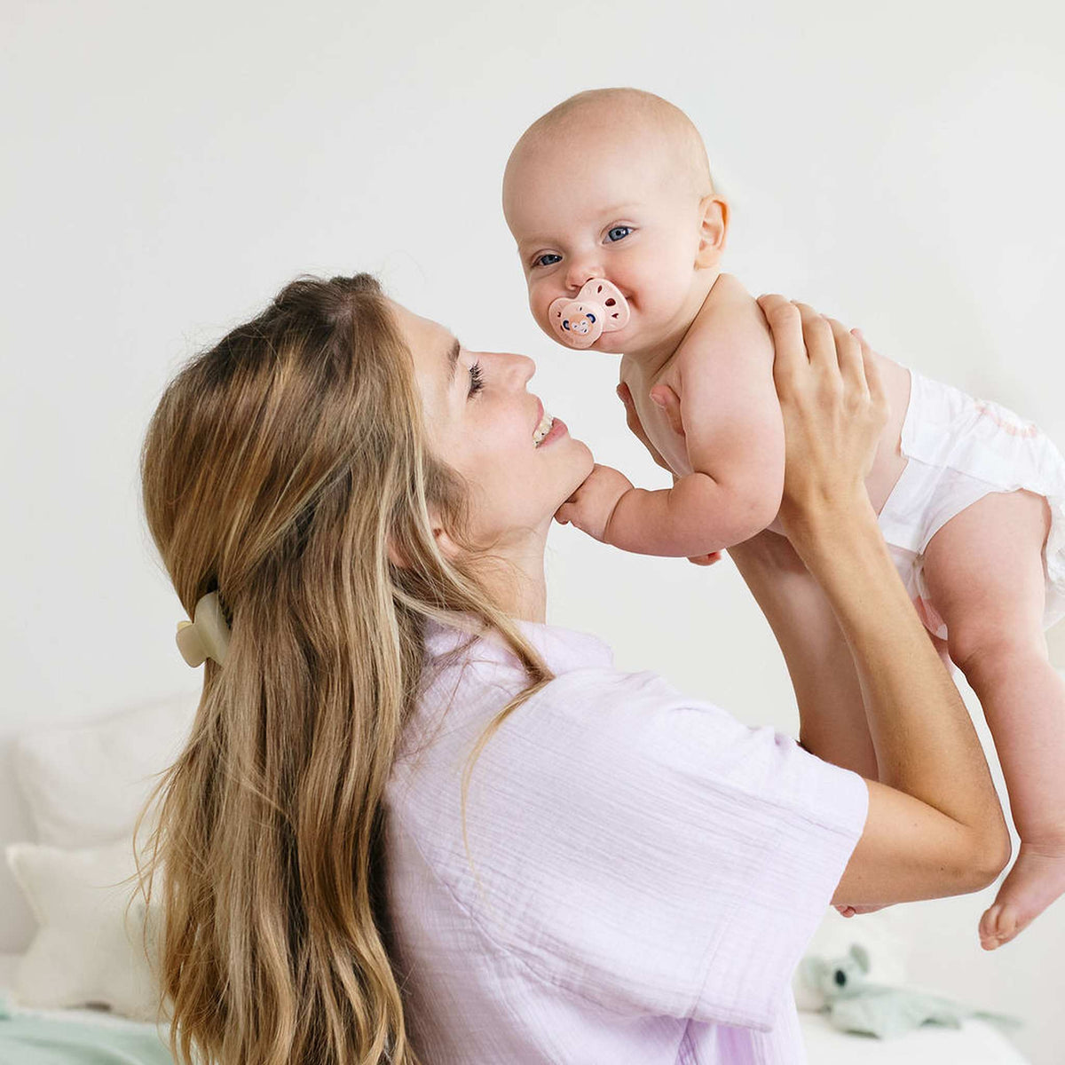 Bébé en couche Biolane soulevé dans les bras de sa maman