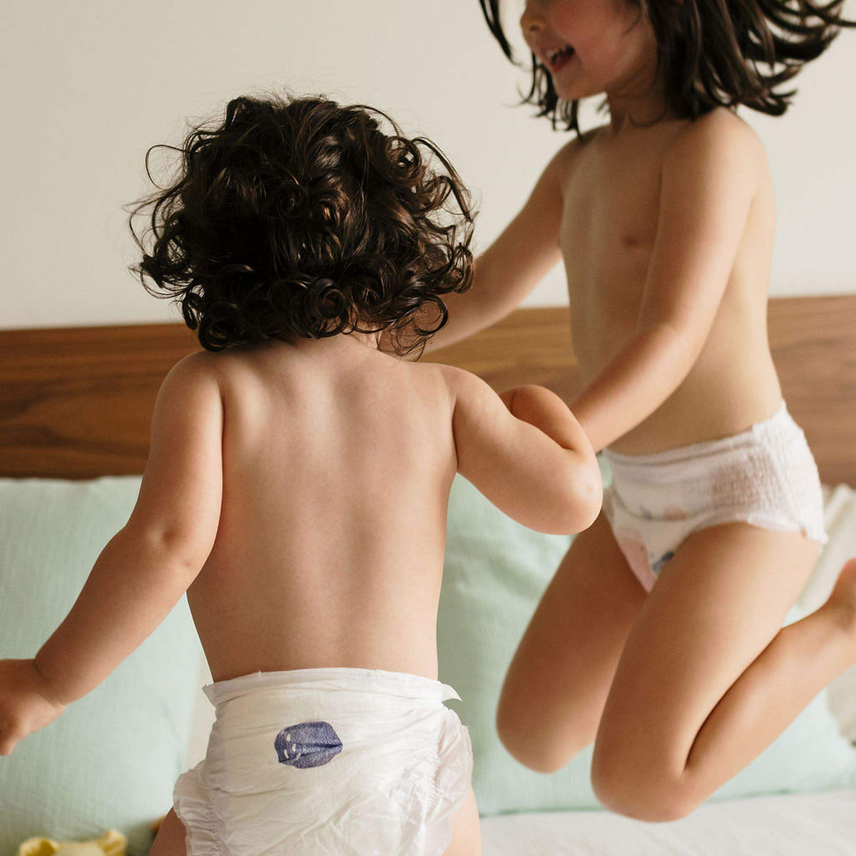 Enfants en couches Biolane jouant sur un lit