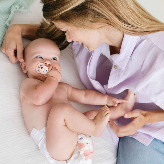 Un bébé en couche Biolane à motifs roses, complice avec sa maman