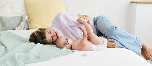 Une femme est allongée sur un lit avec son bébé.