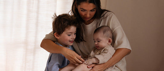 Une maman avec ses deux enfants dans les bras.
