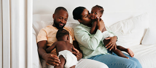 Deux parents sur un canapé avec leurs deux enfants.